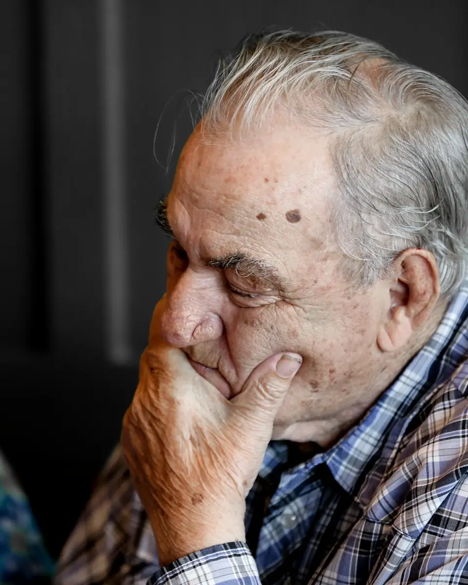 Older man, hand to mouth, pensive