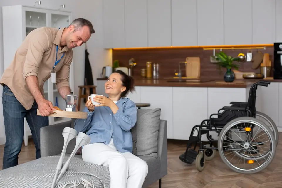 Carer helping older man with cane rise from sofa