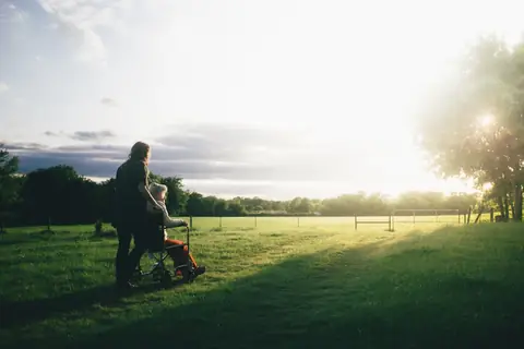 Man serving tea to woman on sofa, wheelchair and crutches