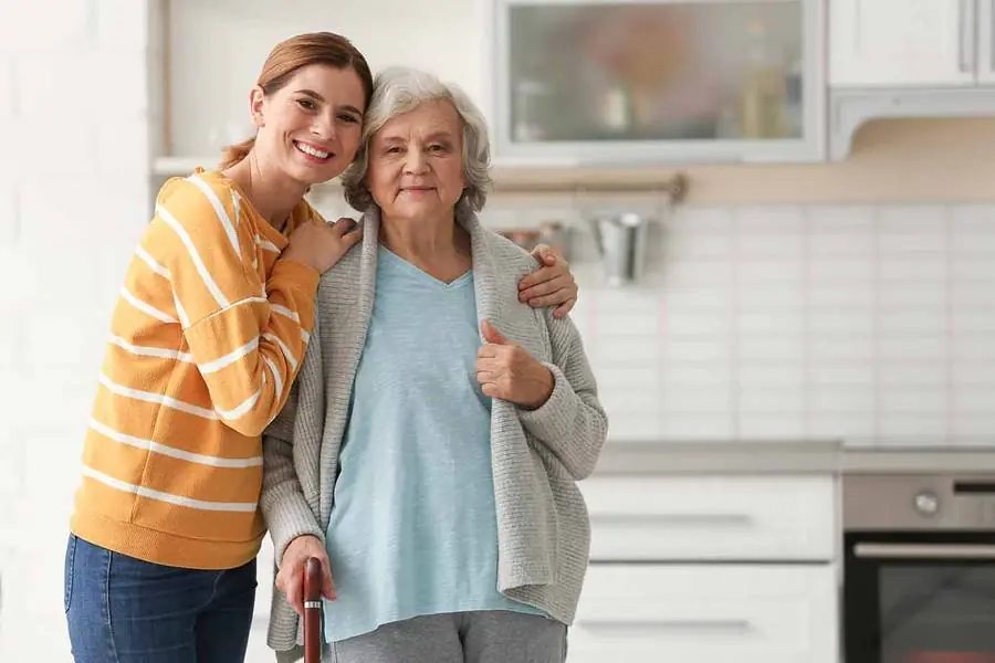 A young woman hugging an older woman in her kitchen, both smiling